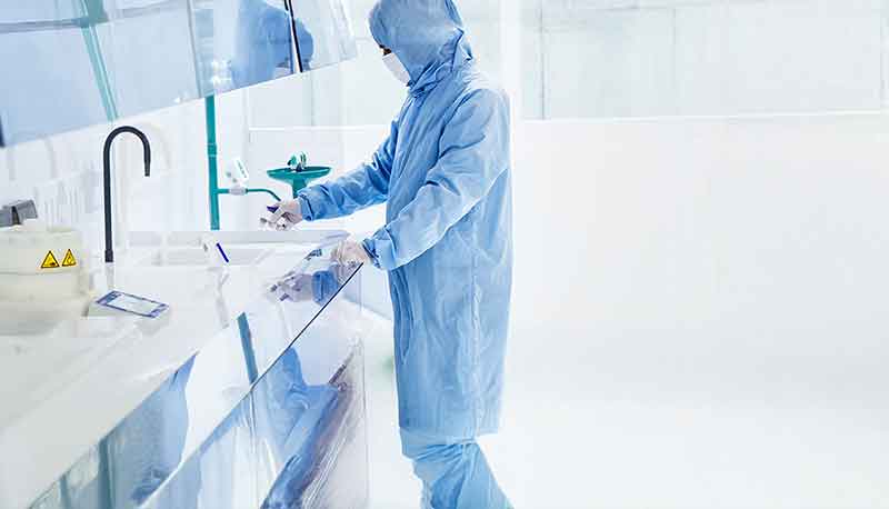 Person at a lab bench wearing head to toe protective clothing