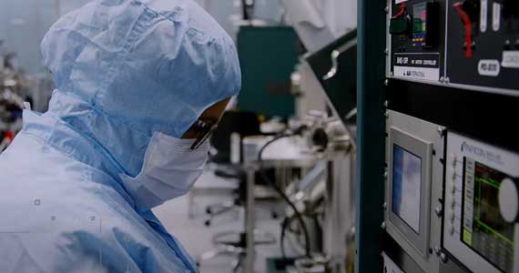 Person in a lab wearing a face mask and lab protective clothing that covers the head.