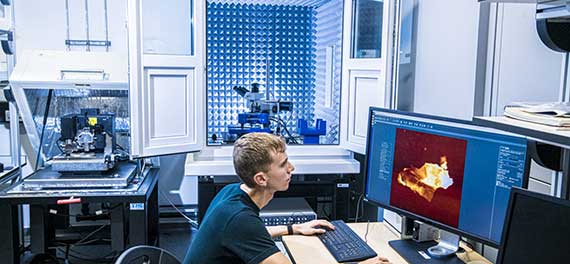 Man beside a powerful surfacing telescope while looking a the results through a computer screen