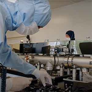 Person operating lab equipment wearing head to toe protective clothing